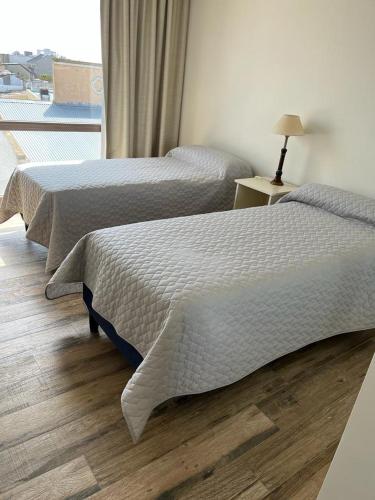 two beds in a hotel room with a window at Departamento Completo Tandil in Tandil