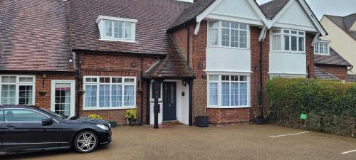 a black car parked in front of a brick house at Hampton Lodge En-Suite Rooms with Free Parking in Stratford-upon-Avon