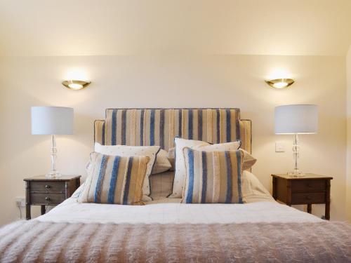 1 dormitorio con 1 cama con cabecero de rayas y 2 lámparas en Stable Cottage - Beaufort Estate, en Belladrum