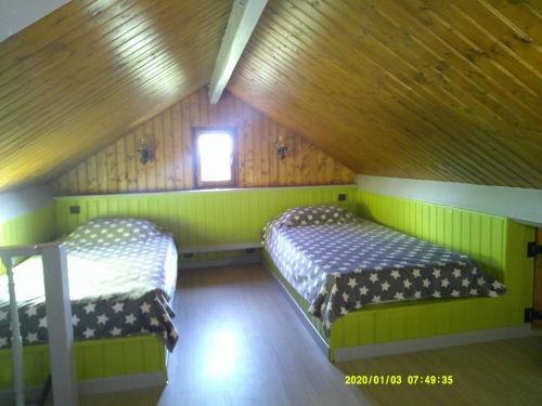 two beds in a room with green walls and a window at a l'orée de tronçais in La Perche