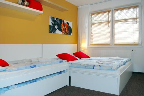 2 łóżka w pokoju z żółtymi ścianami i czerwonymi poduszkami w obiekcie Apartmány Rokytka u sjezdovky w Rokitnicach nad Izerą