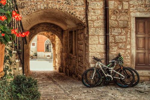 a bike parked next to a building with an archway at Kamene Priče rooms, music and food in Bale