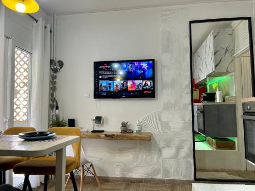 a kitchen with a table and a tv on a wall at Oikiastudios in Patra