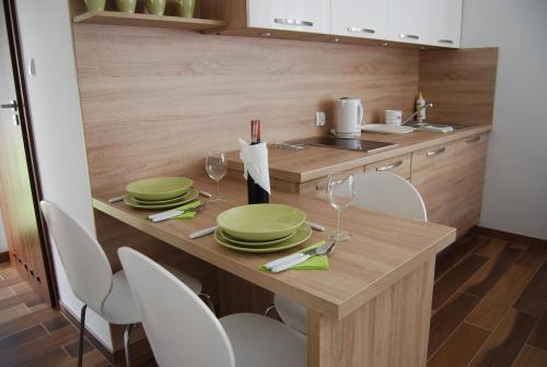 a kitchen with a wooden table with plates and wine glasses at Villa Veell - tylko 4 minuty od pięknej szerokiej plaży in Pobierowo