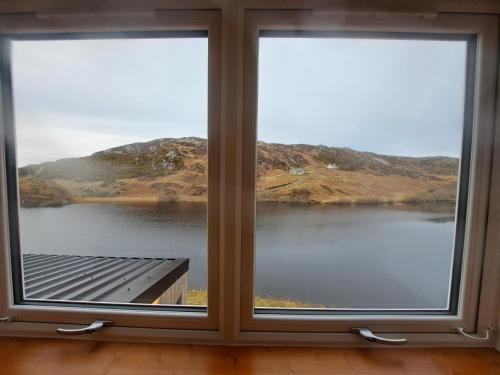 a window with a view of a lake at NC500 - Modern croft house at Handa HI-00734-F in Scourie