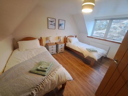 a attic bedroom with two beds and a window at NC500 - Modern croft house at Handa in Scourie