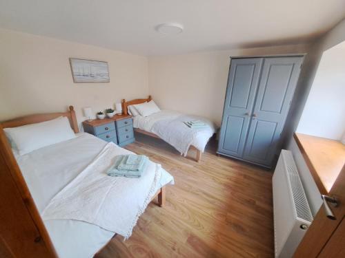 a bedroom with two beds and a blue door at NC500 - Modern croft house at Handa HI-00734-F in Scourie