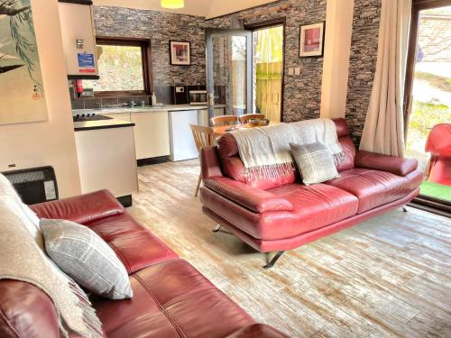 salon ze skórzaną kanapą i kuchnią w obiekcie Primrose 18 Hot Tub-Tenby w mieście Carmarthen