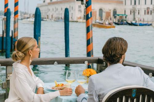 a man and woman sitting at a table with food and wine at The Gritti Palace, a Luxury Collection Hotel, Venice in Venice