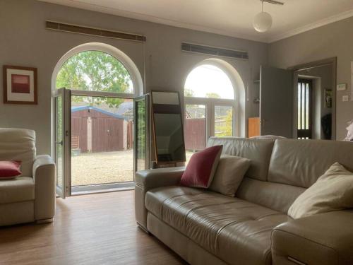 a living room with a couch and an open door at Secret little hideaway - with proximity to Oxford in Cassington