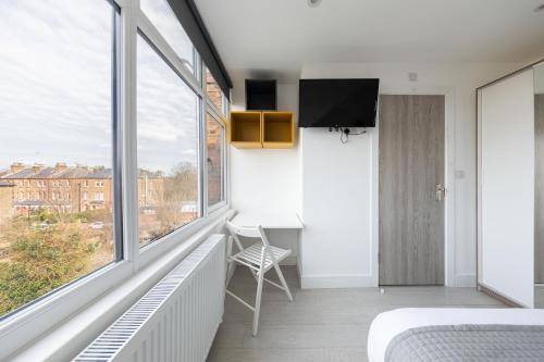 a bedroom with a bed and a desk and windows at Cozy Rooms with Shared Kitchen and Laundry Area in London
