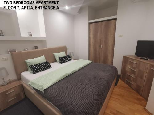 a bedroom with a large bed and a television at Black and White Apartments in Bucharest