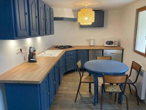 een keuken met blauwe kasten en een blauwe tafel en stoelen bij Au Bois d'Epenin - Gite et Spa in Beugin