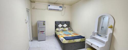 een kleine kamer met een bed en een koelkast bij Abdullah Kamber Building in Dubai