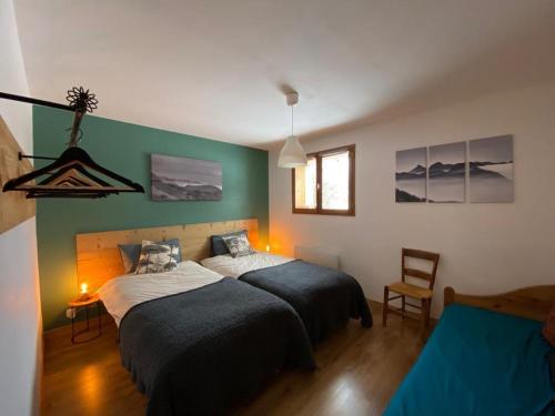 twee bedden in een slaapkamer met groene en witte muren bij LE RUCHER DE LA VIGNETTE in Le Grand-Bornand