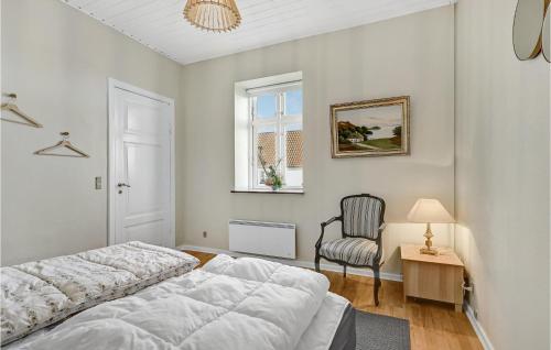 een witte slaapkamer met een bed en een stoel bij Amazing Apartment In Allingbro With Kitchen in Allingåbro