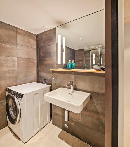 a bathroom with a washing machine and a sink at Liv Suites - Self Check-in in Luzern
