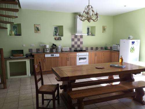 une cuisine avec une table en bois et un réfrigérateur blanc dans l'établissement Gîte rural Le Pressoir, à La Vacquerie