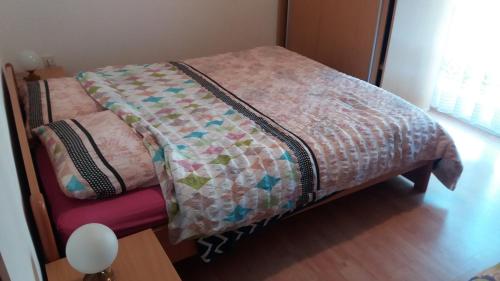 a bed with a quilt on it in a room at Apartmani Stojan in Povljana