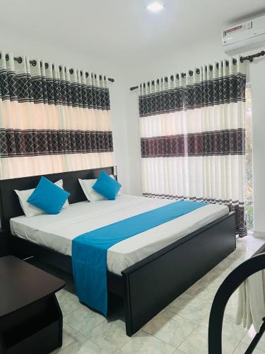 a bedroom with a large bed with blue pillows at White Land City Hotel in Dambulla
