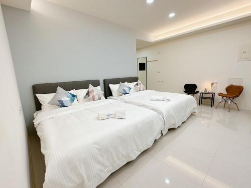 una camera da letto bianca con un grande letto con lenzuola bianche di 芸樂行旅 a Magong
