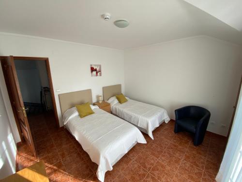 a bedroom with two beds and a blue chair at Ericeira Sand Beach F5 in Ericeira