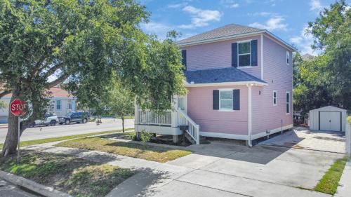 a pink house on a street with a stop sign at Summer Bliss 3BR Home, Walk to Beach Master Suite Sleeps 9 in Galveston