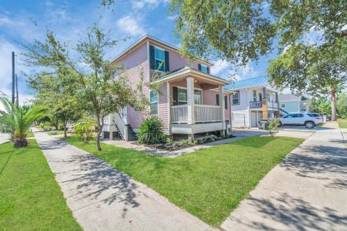 a pink house with a lawn in front of it at Summer Bliss 3BR Home, Walk to Beach Master Suite Sleeps 9 in Galveston