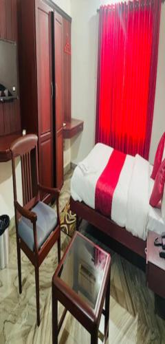 a bedroom with a bed and a chair and a table at Redbell Suites Manjeri in Manjeri