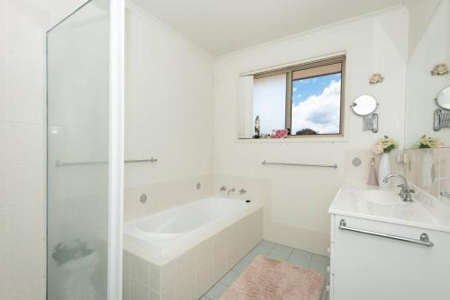 a white bathroom with a tub and a sink at Tranquil Surf Beach apartment. in Surf Beach