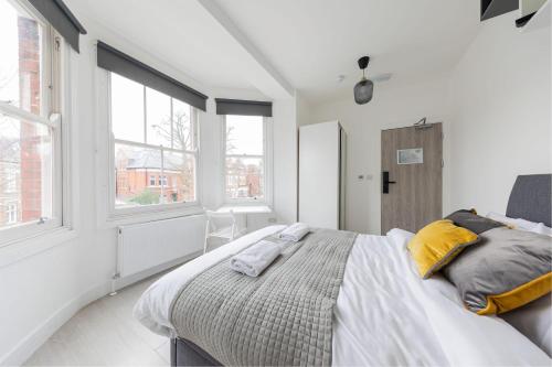 a white bedroom with a large bed with yellow pillows at Garden View Standard Double 5Min Walk To Tufnell Park in London