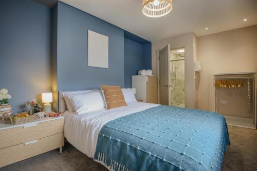 a blue bedroom with a large bed and a dresser at Apartment One - Private Car Park - King Bed - by Ocean City Retreats in Plymouth
