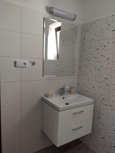 ein weißes Badezimmer mit einem Waschbecken und einem Spiegel in der Unterkunft Apartmán Žďár in Saar