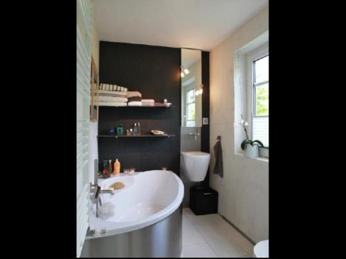 a bathroom with a white tub and a sink at Haus Pünktchen in Tinnum