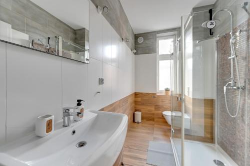 a bathroom with a white sink and a shower at Skandynawski - 4 osobowy apartament przy Monte Cassino by Grand Apartments in Sopot