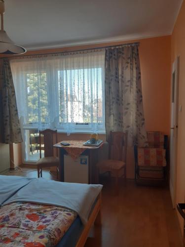 Schlafzimmer mit einem Bett, einem Tisch und einem Fenster in der Unterkunft Pokoje Magda in Władysławowo
