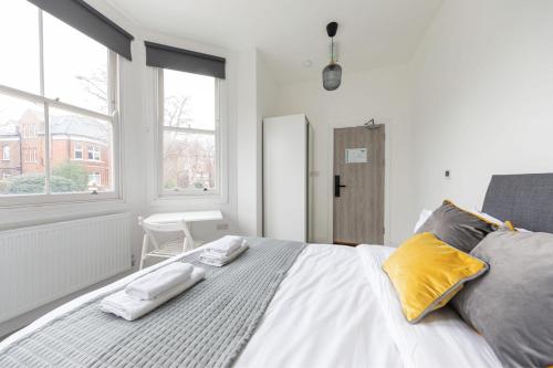 a white bedroom with a large bed with yellow pillows at The Anson Hotel - Conveniently Located Sweet Space Near Transportation Stations in London