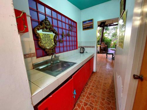 a kitchen with a sink and red cabinets at PROMO: Shabby Chic Countryhome with Huge Garden, Jacuzzi Pool, Mini Billiards, Video Karaoke in Tagaytay