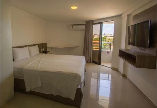 um quarto com uma cama e uma televisão de ecrã plano em Gold Flat Cabo Branco em João Pessoa