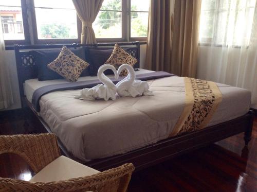 2 cigni seduti su un letto in una camera da letto di Naturbliss Resort Village a Bangkok