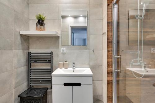 a bathroom with a white sink and a shower at Grand Apartments - Apartamenty Haffnera w samym sercu Sopotu in Sopot