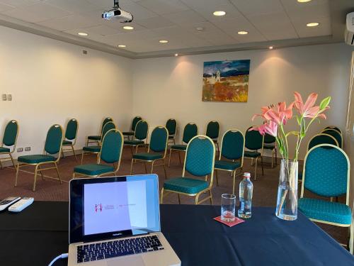 a conference room with a table with a laptop and chairs at Hotel Agua del Desierto in Calama