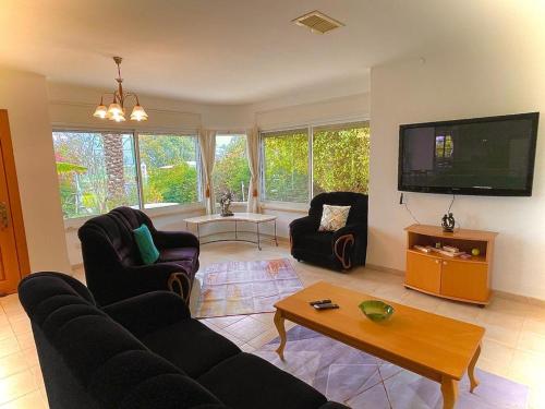a living room with couches and a flat screen tv at וילת שגיא - חופשה כפרית ליד הכנרת - Sagi Villa in Yavneʼel