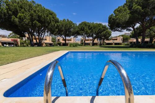 a swimming pool with two metal rails in a yard at Casa de Férias com piscina - Condominio Vilamouraténis in Vilamoura