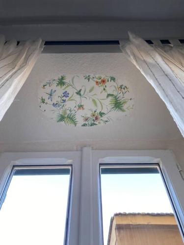 a painting on the ceiling of a room with two windows at Casa Selli in Monte Compatri
