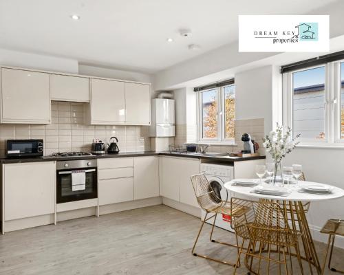 a kitchen with white cabinets and a table with chairs at Two Bedroom Apartment by Dream Key Properties Short Lets & Long Lets Uxbridge- 6 in Uxbridge