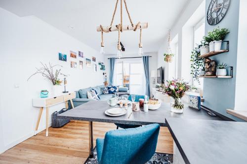 een eetkamer en een woonkamer met een tafel en blauwe stoelen bij Ferienwohnung Sunset bei Warnemünde in Rostock