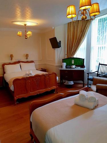 a hotel room with two beds and a television at Rose Tor Hotel in Llandudno