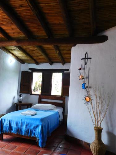 1 dormitorio con 1 cama con colcha azul en Colinas de Barichara, en Barichara