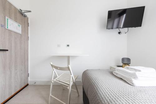 a bedroom with a bed with a chair and a tv on the wall at London Double Bedroom Hotel In Tufnell Park With WiFi in London